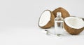 Coconut oil in a bottle with coconuts on a white background. Skin care concept. Face cosmetics. Banner. Copy space