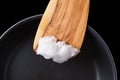 Coconut oil on wooden spatula over coated pan