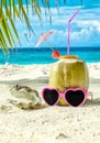 Coconut, pink sunglasses and seashell on sand close-up Royalty Free Stock Photo