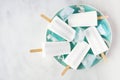 Coconut popsicles on a blue plate over white marble Royalty Free Stock Photo