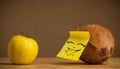 Coconut with post-it note sticking out tongue to apple