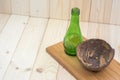 Coconut shell with green glass bottles on splat.