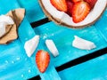 Coconut with strawberries on blue wooden background Royalty Free Stock Photo