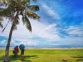 A family outing and coconut tree in the Tanjung Aru Beach, Kota Kinabalu with the beautiful blue sky above on sunny day. Royalty Free Stock Photo