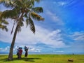 A family outing and coconut tree in the Tanjung Aru Beach, Kota Kinabalu with the beautiful blue sky above on sunny day. Royalty Free Stock Photo