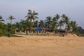 coconut trees on ocean coast near tropical shack or open cafe on beach with sunbeds