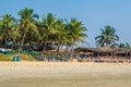 coconut trees on ocean coast near tropical shack or open cafe on beach with sunbeds