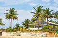 coconut trees on ocean coast near tropical shack or open cafe on beach with sunbeds Royalty Free Stock Photo