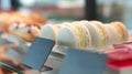 Coconut or vanilla macaroons and other desserts in a glass showcase in a cafe or shop. Selective focus