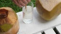 Coconut water pouring from fresh whole coconut into glass