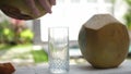 Coconut water pouring from fresh whole coconut into glass