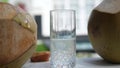 Coconut water pouring from fresh whole coconut into glass