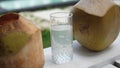 Coconut water pouring from fresh whole coconut into glass