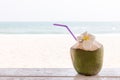 Coconut on wooden floor with sea background. Tropical fresh coconut cocktail decorated plumeria on white beach. Royalty Free Stock Photo