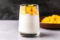 coconut yogurt mixed with diced mango in a tall glass