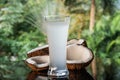 Coconuts and coconut water on the black glass table isolated over blurred palm trees background Royalty Free Stock Photo