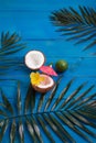 Coconuts and palm leaves on blue wooden background. Flat lay, space for text