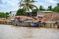 Wooden cargo boat delivering coconut shells to factory on distributary of Mekong Delta, Vietnam