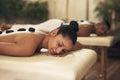 Cocoon yourself in a little sanctuary of bliss. a young woman getting a hot stone massage at a spa. Royalty Free Stock Photo