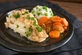 Cod fillet with parsley garnish, carrots and green pea rice on a dark plate, healthy fish meal, selected focus, very narrow depth