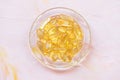 Cod liver fish oil capsules in glass bowl on pink Royalty Free Stock Photo