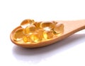 Cod liver oil omega 3 gel capsules in wood spoon  isolated on white background Royalty Free Stock Photo