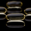 Cod liver vitamin D capsules on black reflective surface