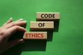 Code of ethics symbol. Concept words Code of ethics on wooden blocks. Beautiful green background. Businessman hand. Business and Royalty Free Stock Photo