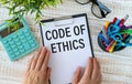 Code of Ethics text written on notepad with pencil. Notepad on a folder on wooden background Royalty Free Stock Photo