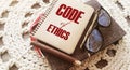 Code Of Ethics words on notebook, pen, glasses, crochet cloth. Business concept. Moral Rules Ethical Integrity Honesty Good