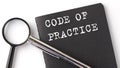 CODE OF PRACTICE - business concept, magnifier with white text message on black notebook