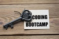 CODING BOOTCAMP - words on white paper on a wooden background with a beautiful key