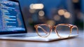 Coding on laptop with glasses on keyboard in office environment