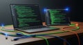 Coding setup with multiple monitors displaying green code and network cables on a wooden desk Royalty Free Stock Photo