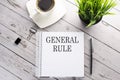 Cofee cup, notepad,pen on the wooden background. Business concept. Text GENERAL RULE