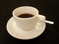 Coffe black on the table with small spoon and dark table