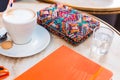 Coffe cappuccino, orange notebook, glass of water and colorful accessories