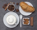 Coffe, a cup of hot latte or cappuccino with bun, top view. Background plate made from natural slate. Coffe beans, sugar Royalty Free Stock Photo