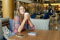 Coffee addict portrait. Joyful woman hugs a white disposable coffee cup in a cafe
