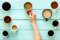 Coffee addiction. Mug in hand, many cups on green wooden desk top-down