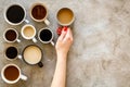 Coffee addiction. Mug in hand, many cups on grey background top view copy space