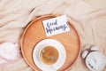 Coffee, alarm clock and note with text Good Morning, top view