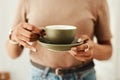 Coffee anyone. an unrecognizable woman standing alone in her home and holding a cup of coffee. Royalty Free Stock Photo