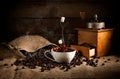 coffee art composition: scattered roasted beans from a bag, coffee grinder with ground coffee and a cup of coffee with a splash o Royalty Free Stock Photo
