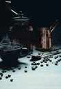 Coffee background of a cup of hot coffee on table with coffee grinder and coffee jar and roasted coffee beans in dark dimming