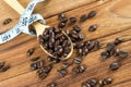 Coffee bean on wooden spoon, tape measure on wooden background Royalty Free Stock Photo