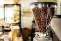 Coffee beans in a big glass grinder machine holder with blurred background of a cafe Royalty Free Stock Photo