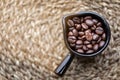 The coffee beans are in a black ceramic glass on a blurred wooden table. Shot from high angle close up shot. Royalty Free Stock Photo