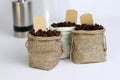 Coffee beans in burlap bags with blank labels on white background.