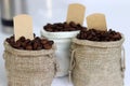 Coffee beans in burlap bags with blank labels on white background.